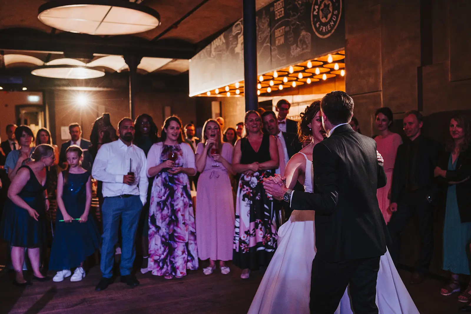 Brautpaar tanzt ihren Eröffnungstanz bei der Hochzeit im Liebesbier Bayreuth, umgeben von Gästen.