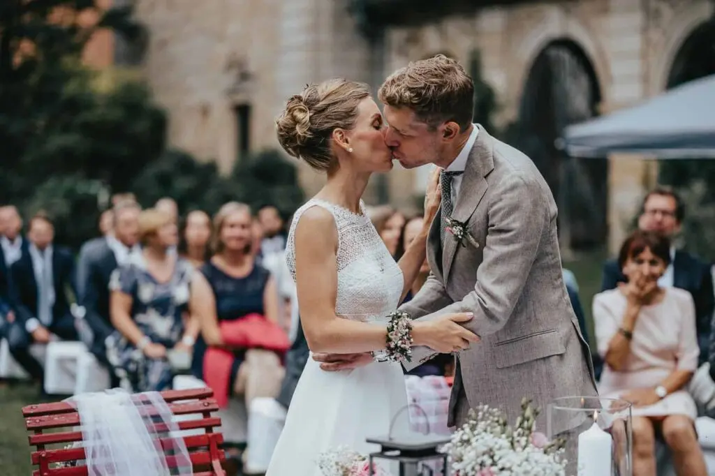 Das Brautpaar küsst sich nach der Zeremonie vor den Gästen im Garten